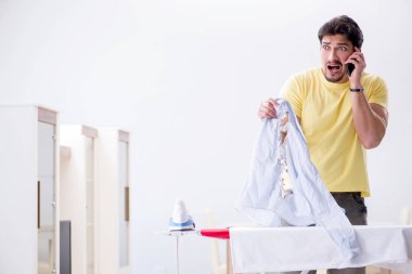 Yakışıklı koca evde kıyafet ütülüyor.