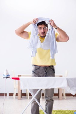 Yakışıklı koca evde kıyafet ütülüyor.