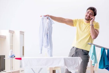 Yakışıklı koca evde kıyafet ütülüyor.