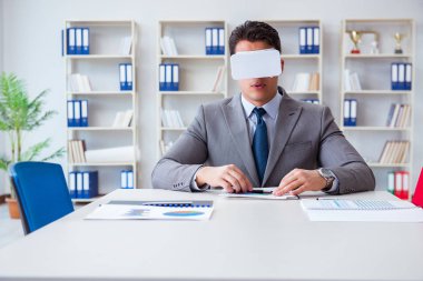Ofiste sanal gerçeklik gözlüklü bir iş adamı var.