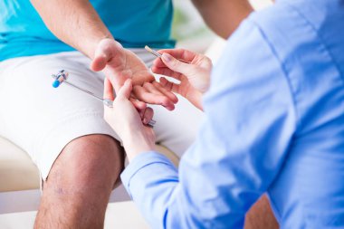 Doktor çekiçle sinir reflekslerini kontrol ediyor