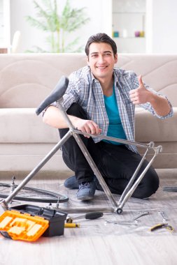 Evde bisiklet tamir eden genç bir adam.