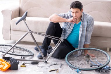 Evde bisiklet tamir eden genç bir adam.