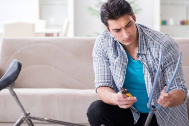 Evde bisiklet tamir eden genç bir adam.