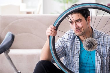 Evde bisiklet tamir eden genç bir adam.