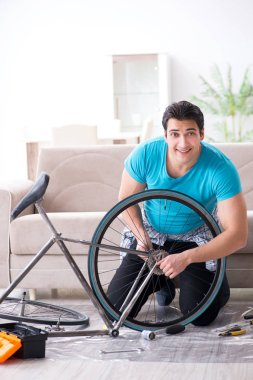 Evde bisiklet tamir eden genç bir adam.