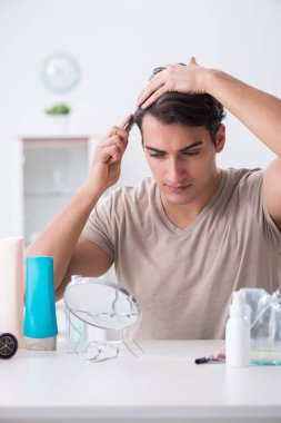 Genç yakışıklı adam aynaya bakıyor. 