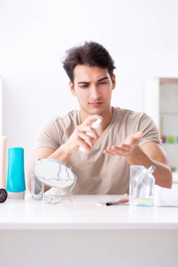 Genç yakışıklı adam aynaya bakıyor. 