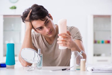 Genç yakışıklı adam aynaya bakıyor. 