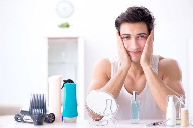 Genç yakışıklı adam aynaya bakıyor. 