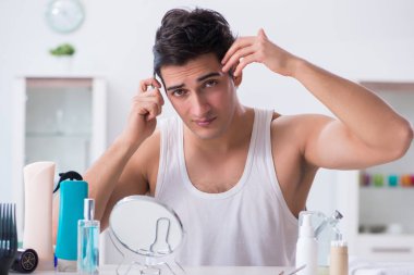 Genç yakışıklı adam aynaya bakıyor. 