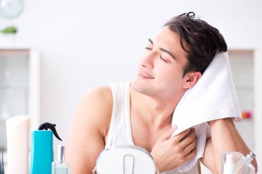 Genç yakışıklı adam aynaya bakıyor. 