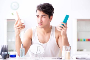 Genç yakışıklı adam aynaya bakıyor. 