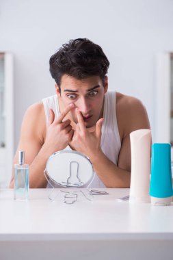 Genç yakışıklı adam aynaya bakıyor. 