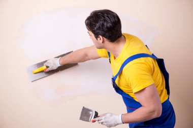 Young contractor employee applying plaster on wall clipart