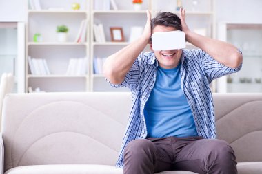 Evde sanal gerçeklik gözlüklü bir adam oynuyor.