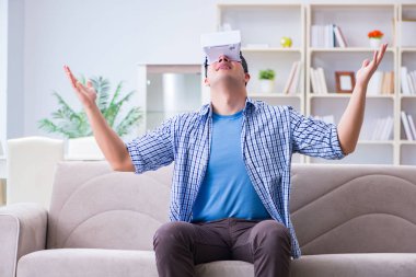 Evde sanal gerçeklik gözlüklü bir adam oynuyor.
