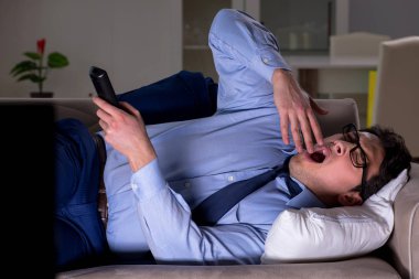 İşadamı gece geç saatte televizyon izliyor.