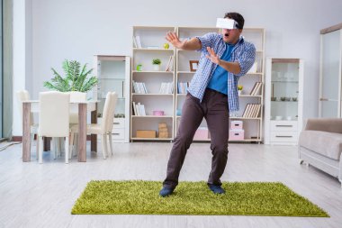 Evde sanal gerçeklik gözlüklü bir adam oynuyor.