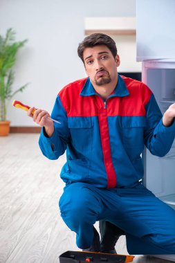 Profesyonel müteahhit bozuk buzdolabını tamir ediyor.