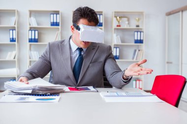 Ofiste sanal gerçeklik gözlüklü bir iş adamı var.
