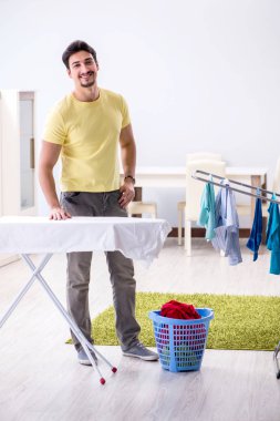 Yakışıklı koca evde kıyafet ütülüyor.