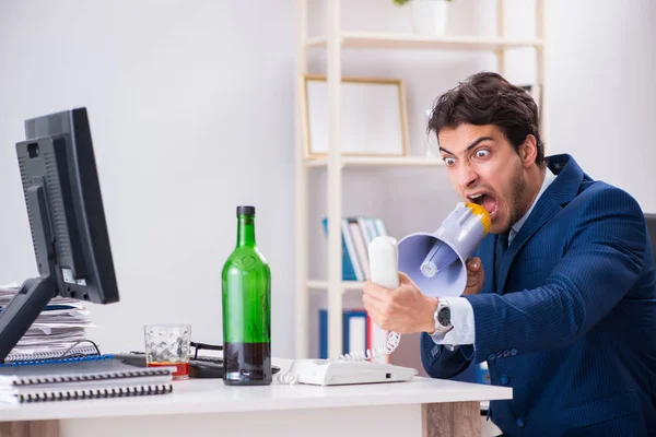 Jovem empresário empregado bebendo no escritório na mesa — Fotografia de Stock