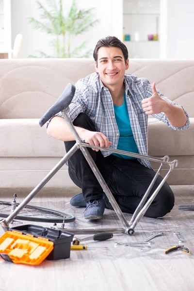 Evde bisiklet tamir eden genç bir adam.