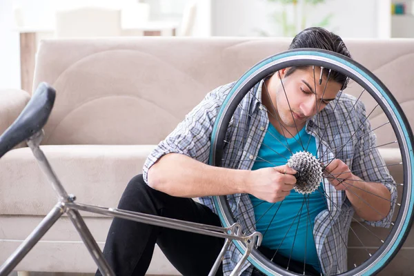 Evde bisiklet tamir eden genç bir adam.