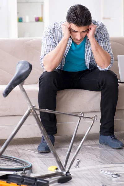 Evde bisiklet tamir eden genç bir adam.