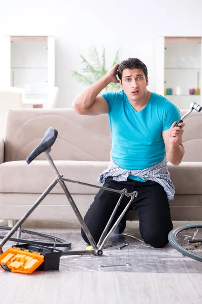 Evde bisiklet tamir eden genç bir adam.