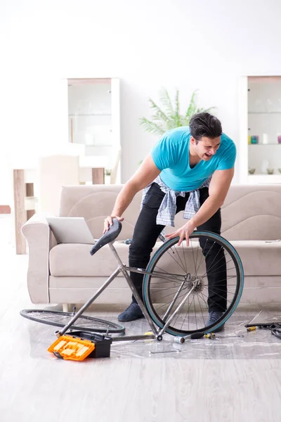 Evde bisiklet tamir eden genç bir adam.
