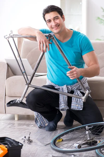 Evde bisiklet tamir eden genç bir adam.
