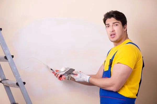 壁に石膏を適用若い請負業者の従業員 — ストック写真