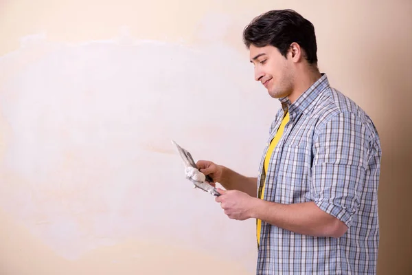 Junger Mann putzt zu Hause Wand auf — Stockfoto