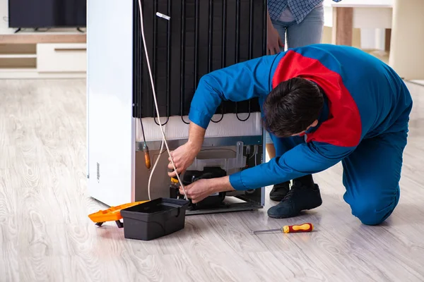 Man repairing fridge with customer