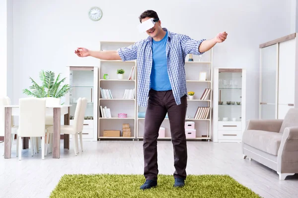 Evde sanal gerçeklik gözlüklü bir adam oynuyor.