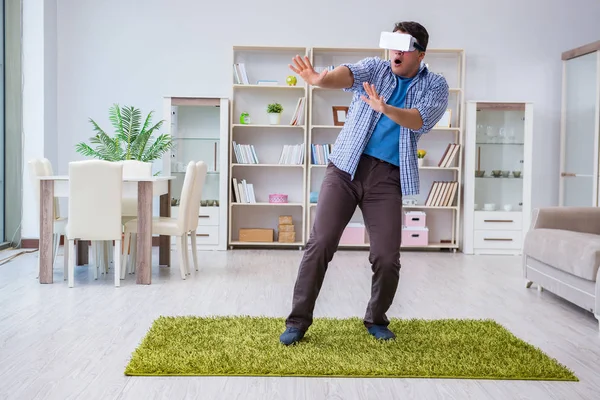 Evde sanal gerçeklik gözlüklü bir adam oynuyor.