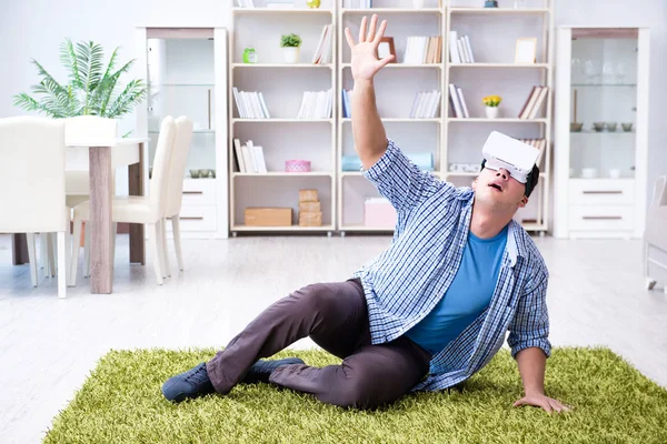 Evde sanal gerçeklik gözlüklü bir adam oynuyor.