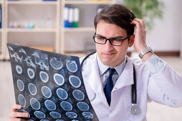 Junger Arzt schaut sich Röntgenbilder in Klinik an — Stockfoto
