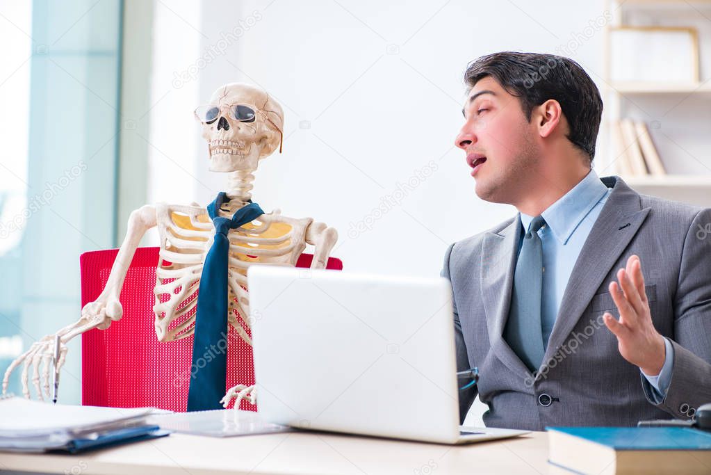 Businessman working with skeleton in office