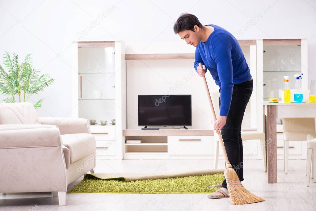 Young man cleaning floor with broom