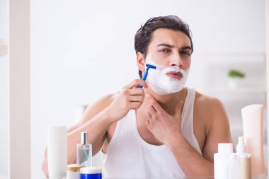 Genç yakışıklı adam sabah erkenden tıraş oluyor.