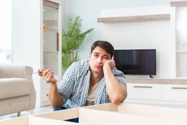 Adam evde mobilya montajı yapıyor.