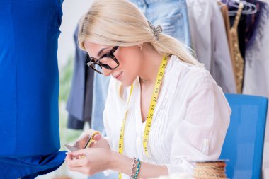 Yeni elbise tasarımları üzerinde çalışan kadın terzi.