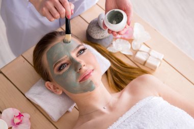 Yüz maskeli, spa sağlık konsepti olan genç bir kadın.