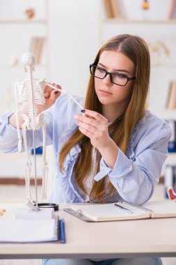 Öğrenci sınıfında oturuyor ve iskelet çalışıyor.