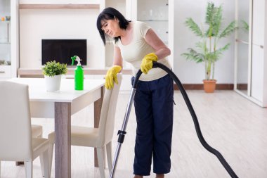 Yaşlı kadın elektrik süpürgesinden yorgun düştü.