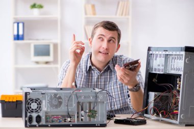 Genç teknisyen atölyede bilgisayar tamir ediyor.