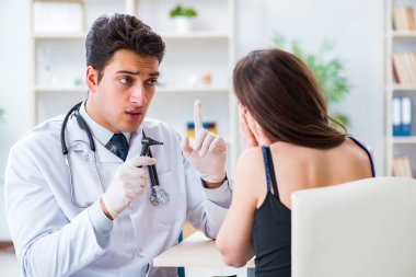 Doktor muayene sırasında hastaların kulaklarını kontrol ediyor.